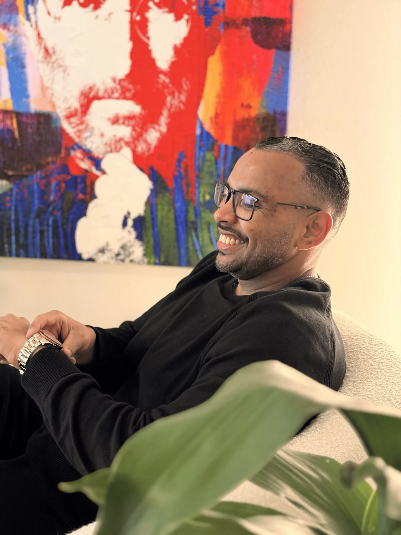 Anardo Cuello seated in front of a Steve Jobs artwork